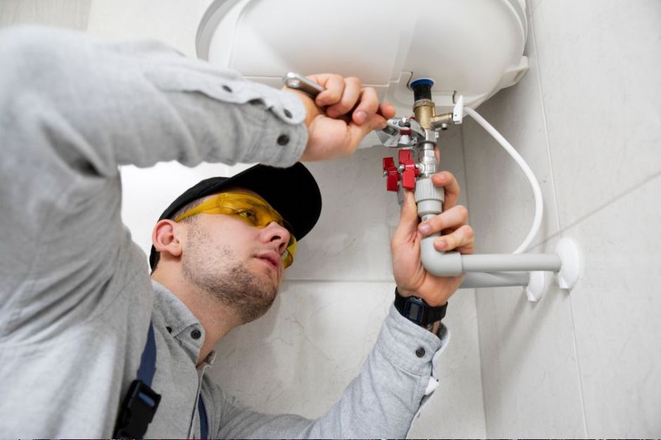 A boiler repairer repairing a boiler under a sink